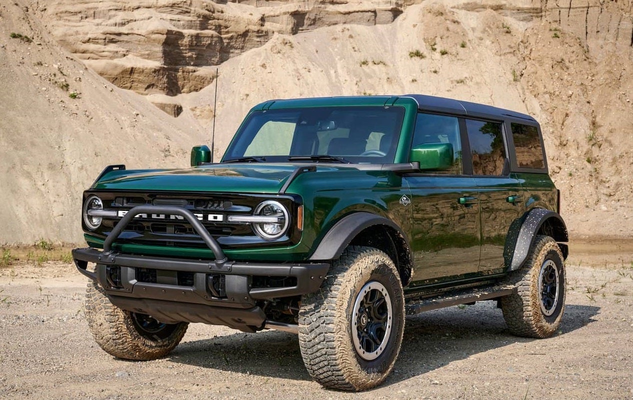 A dark green 2023 Ford Bronco Raptor SUV parked at the base of a sandy cliff