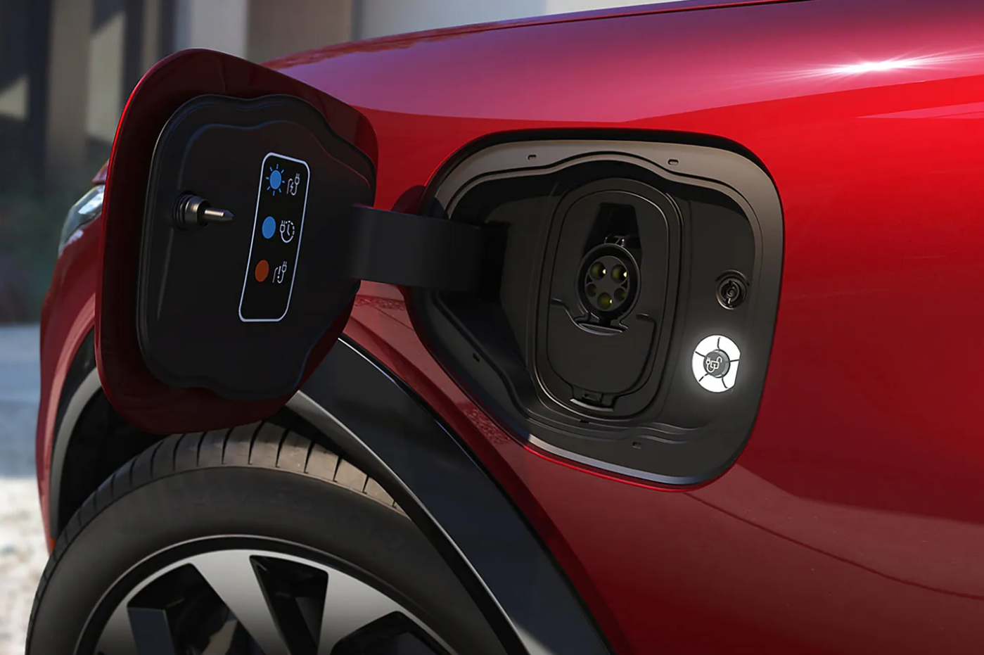 The charging port door on a red 2022 Ford Mach-E is opened and revealing the charging port on the side of the vehicle