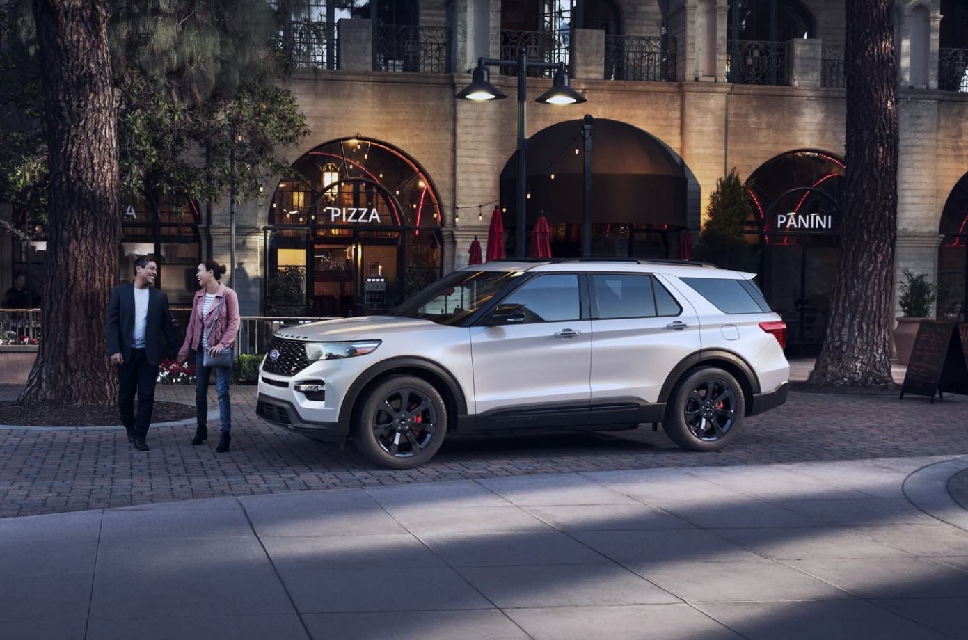 A profile view of a white 2023 Ford Explorer ST parked on a city street.