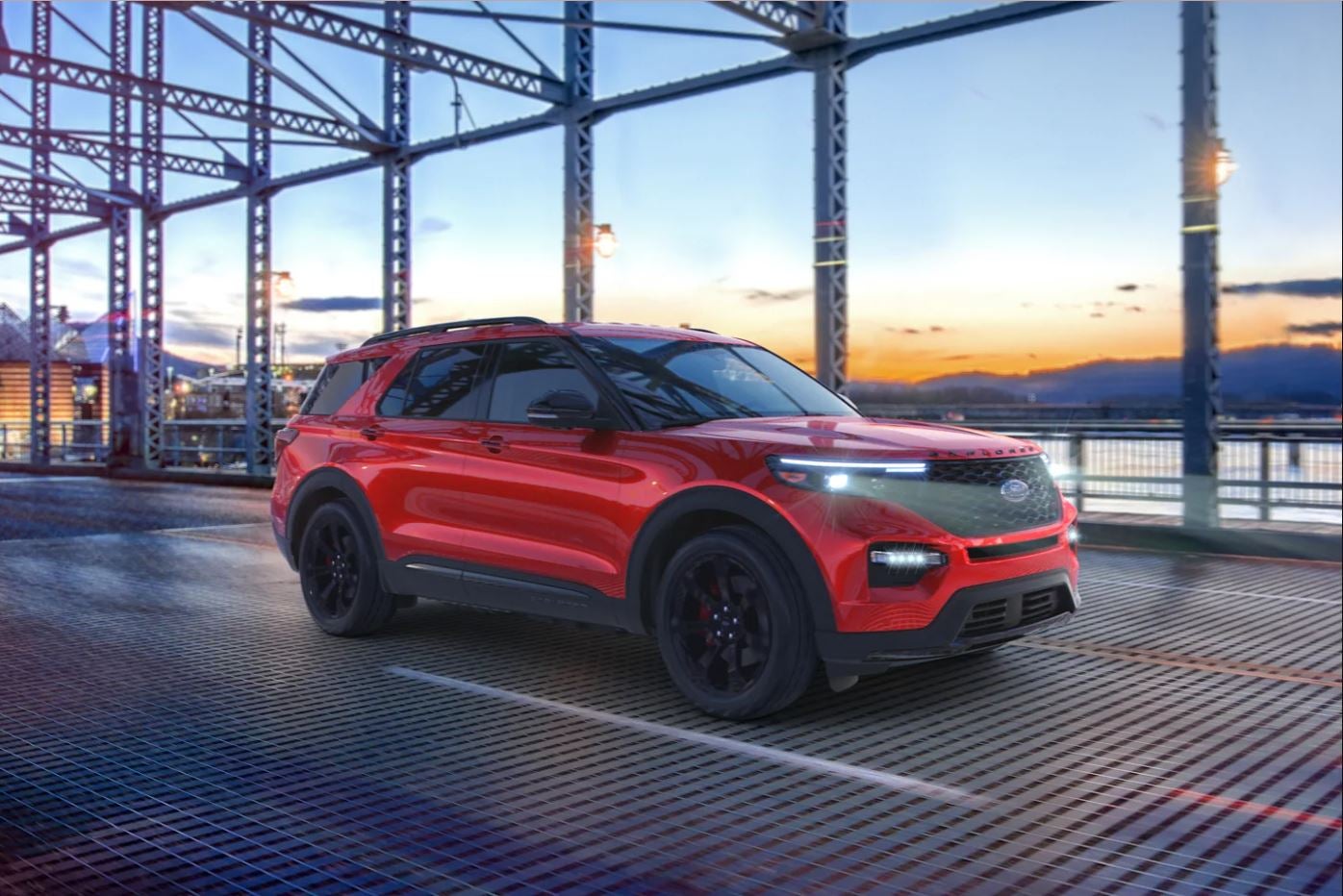 A view of the side and front of a red 2023 Ford Explorer ST as it drives across a bridge