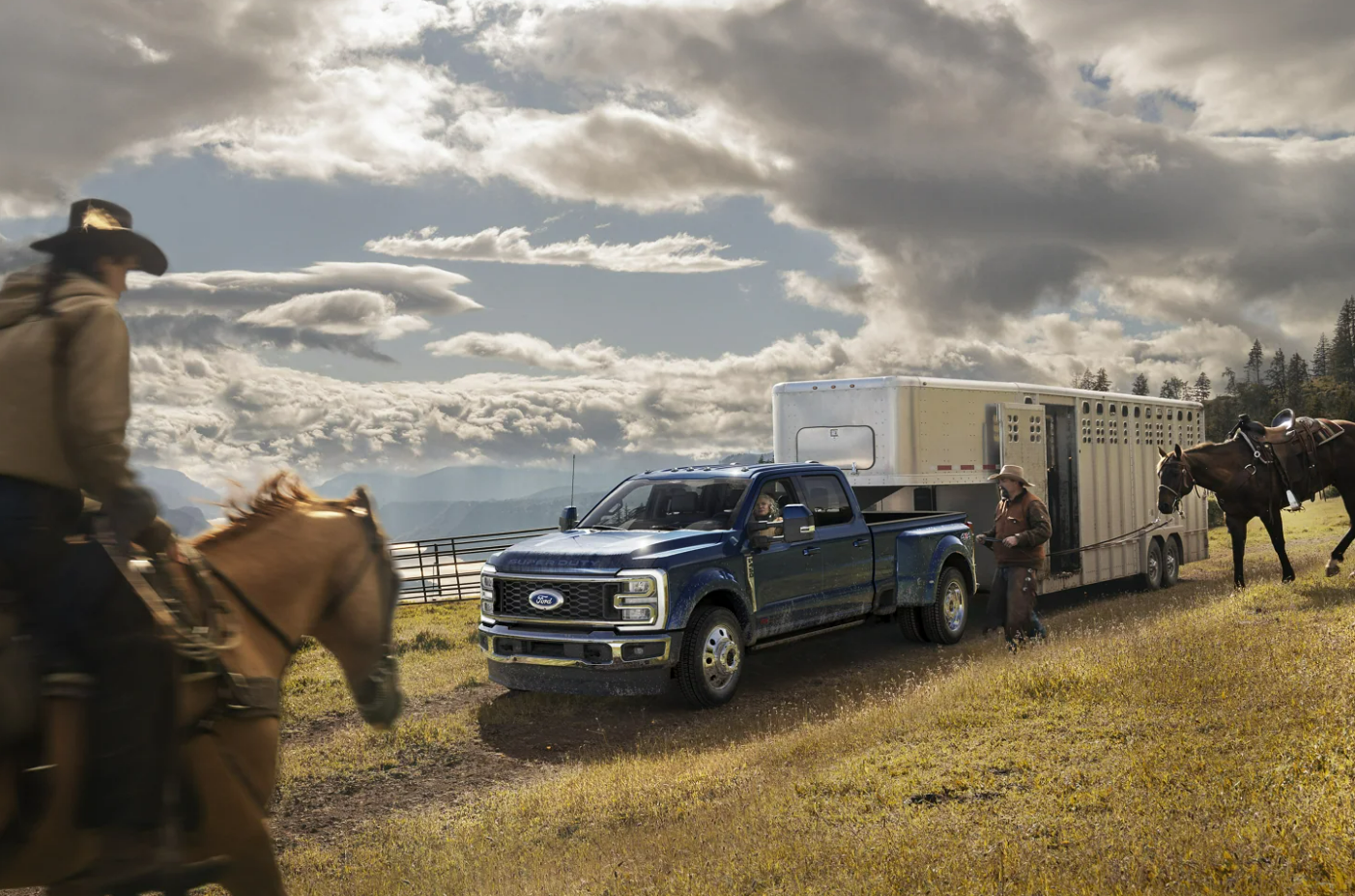 A 2023 Ford F-350 Super Duty hauling a horse trailer is parked in a field