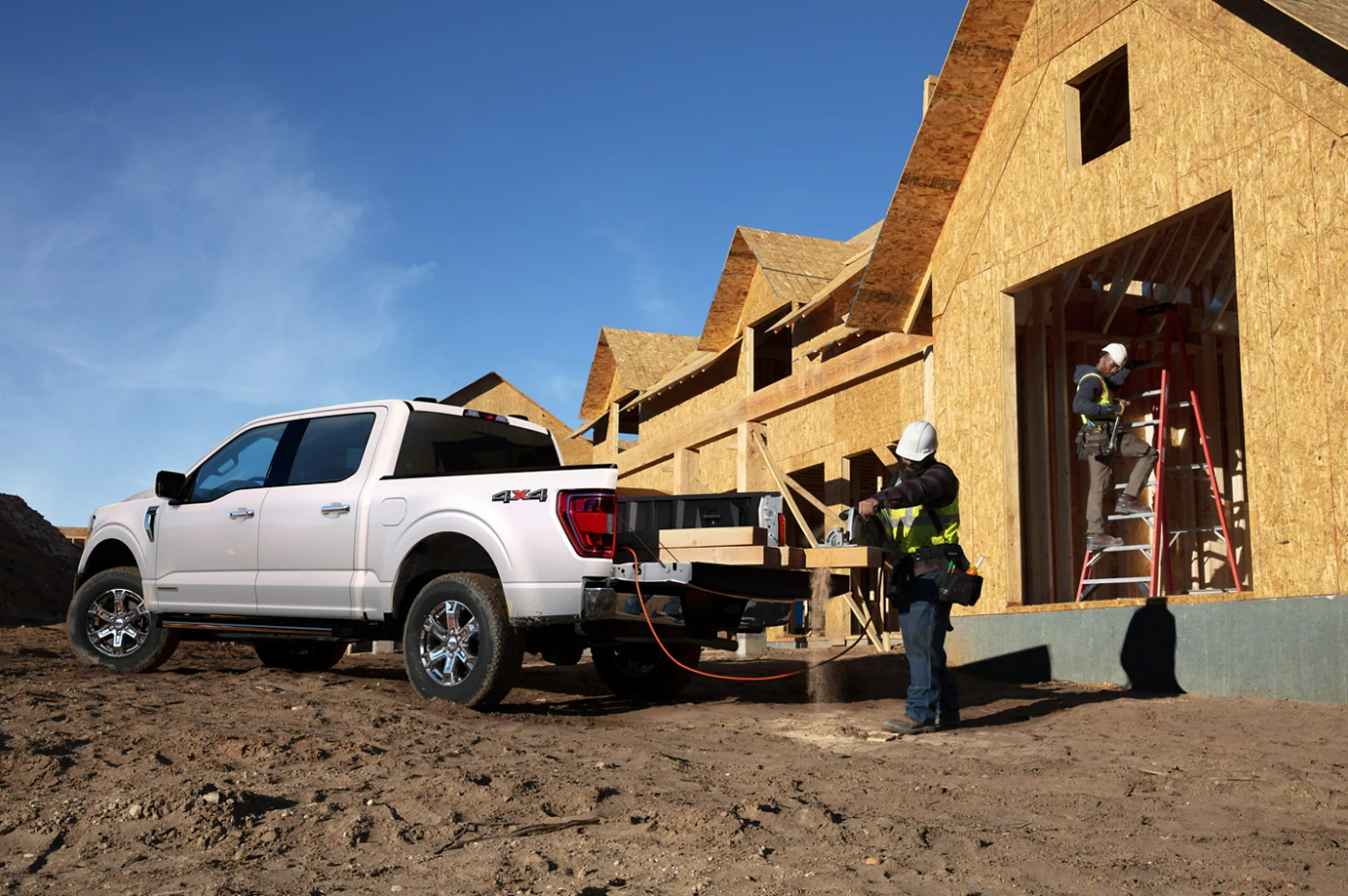 A man cuts lumber for a construction project on the back of a white 2023 Ford F-150