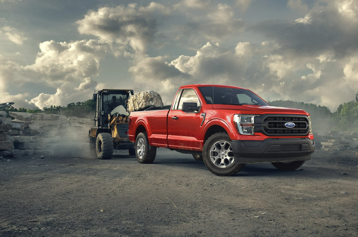 A red 2023 Ford F-150 hauling construction equipment