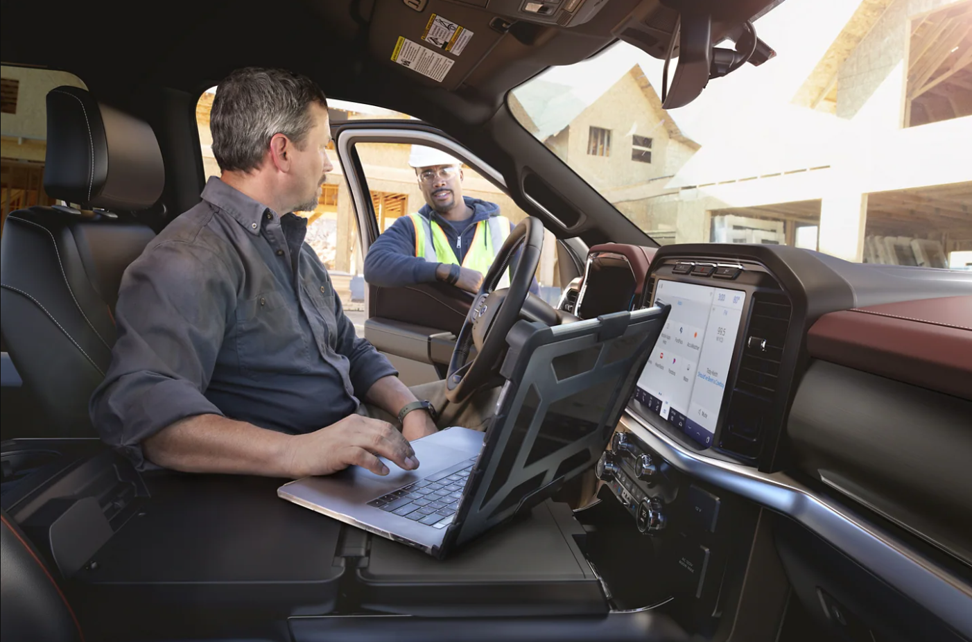 A man uses the center console of his 2023 Ford F-150 Raptor R as a surface for his laptop