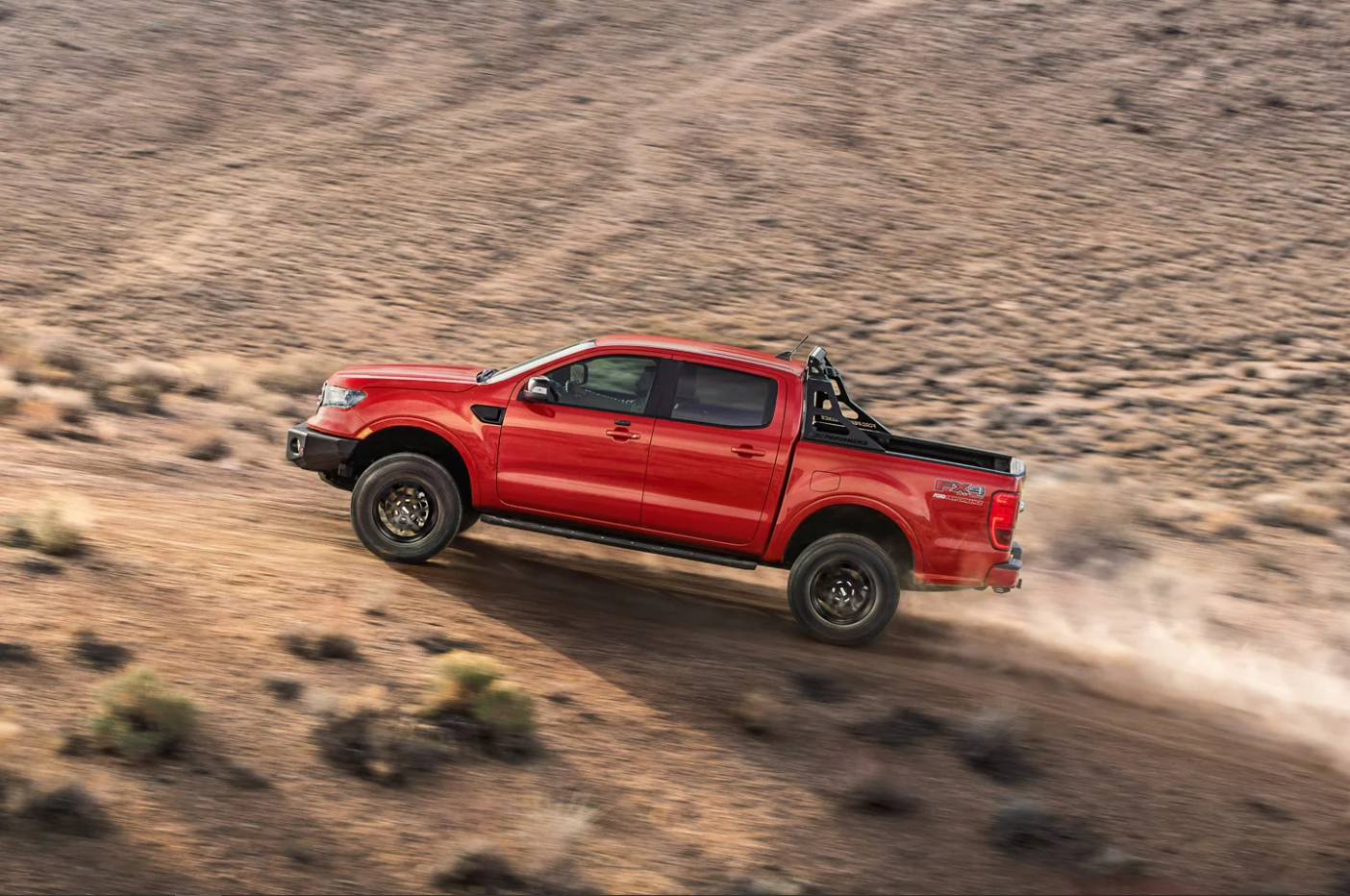 A red 2023 Ford Ranger climbs a dirt hill in a desert