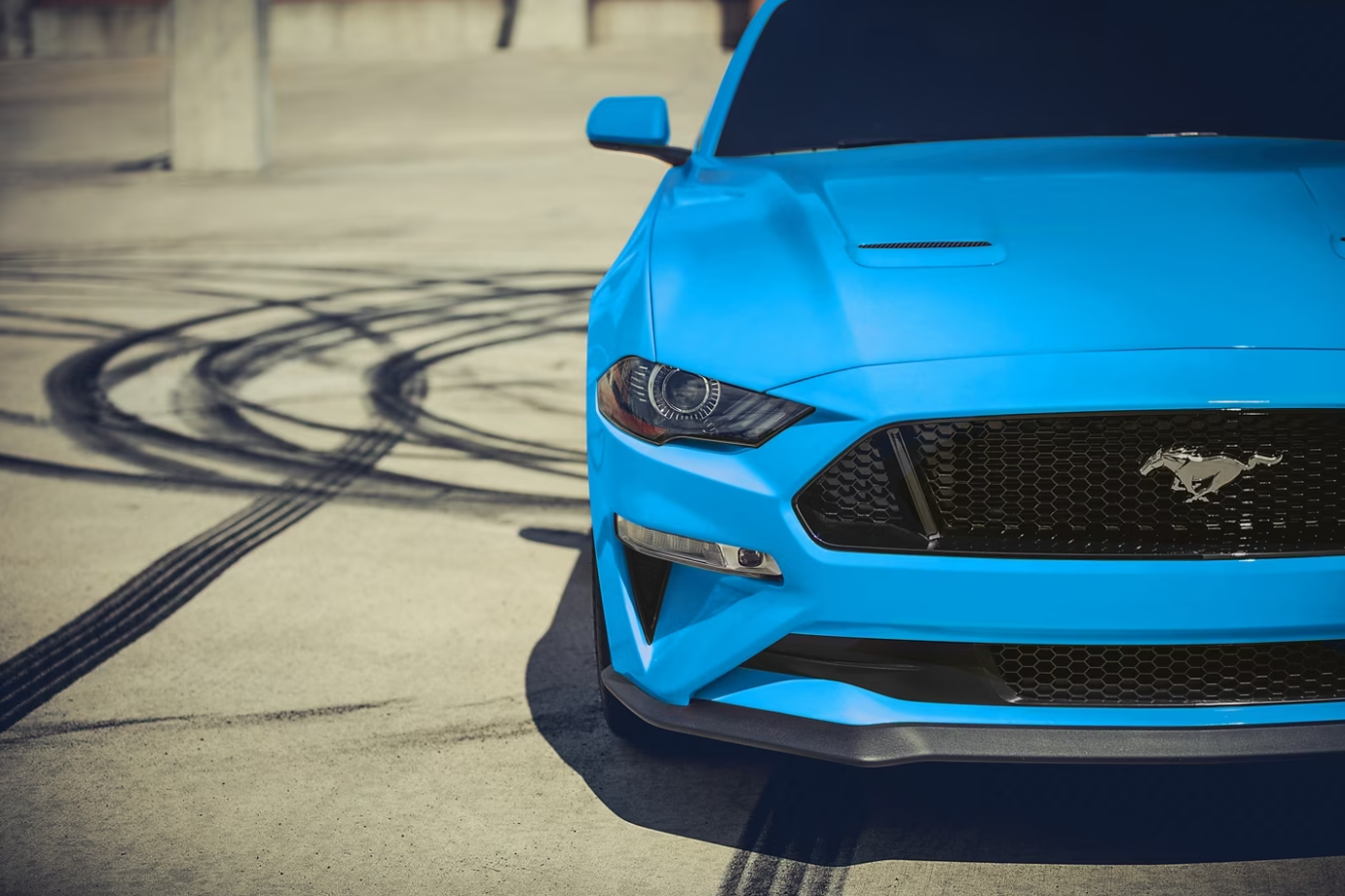A closeup of the front grille of an electric blue 2023 Ford Mustang