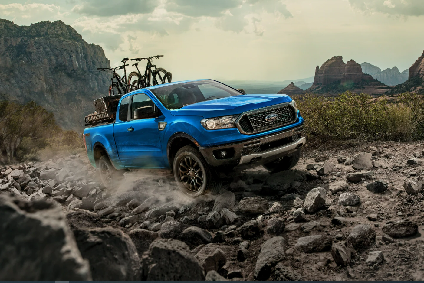 A blue 2023 Ford Ranger tackles a hill of boulders