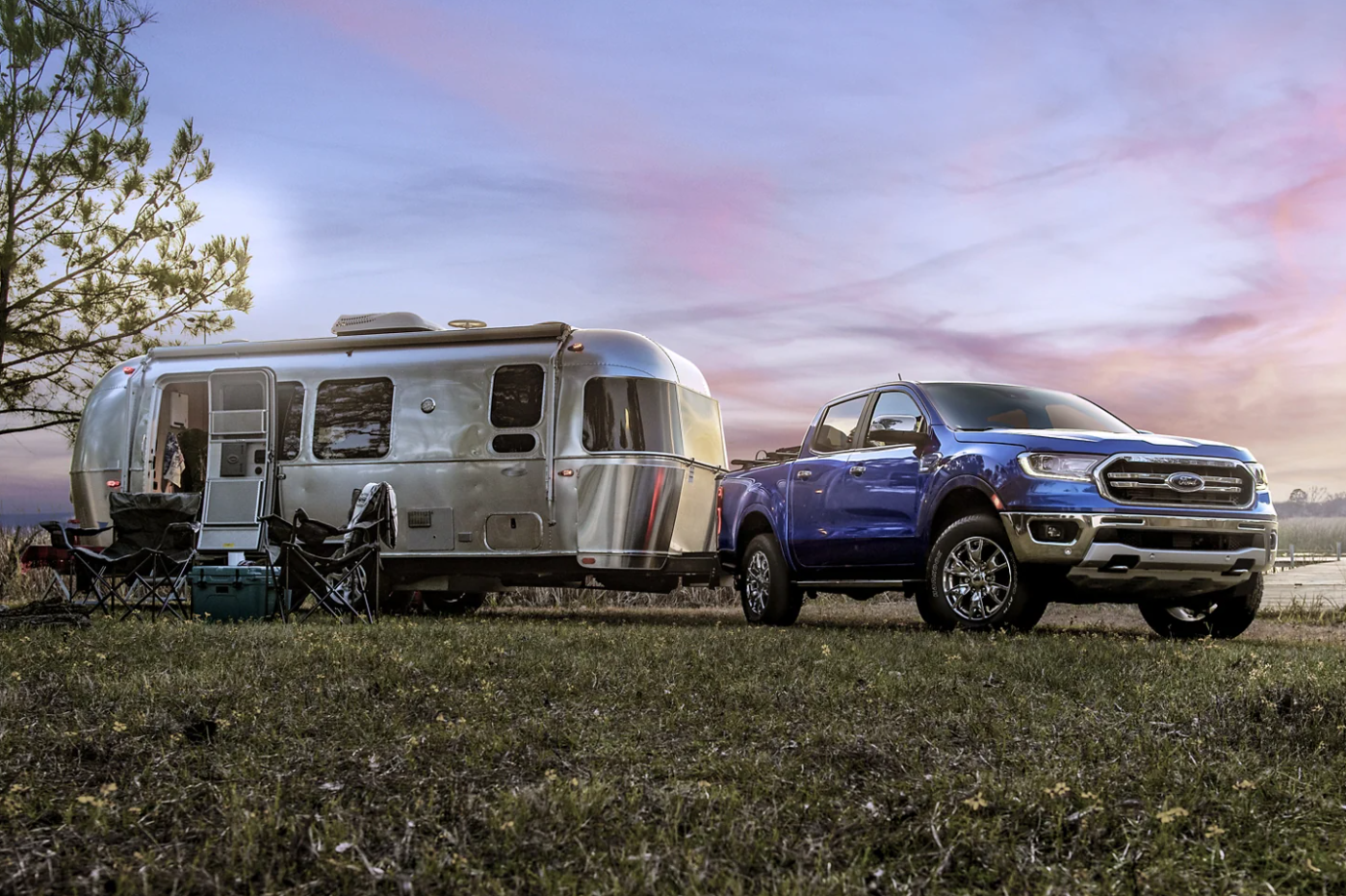 A blue 2023 Ford Ranger is parked after towing an airstream to a campsite