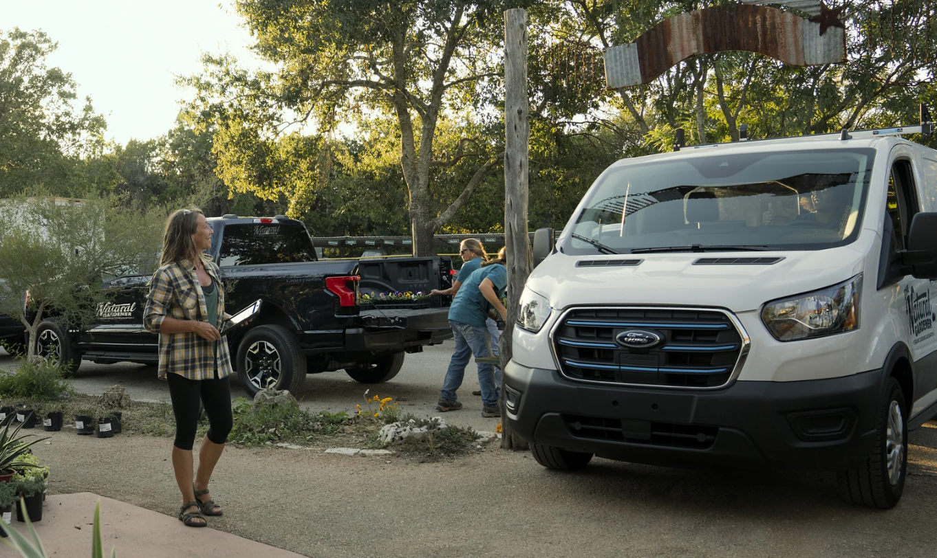 A woman signs for a delivery brought to her driveway in a 2023 Ford E-Series