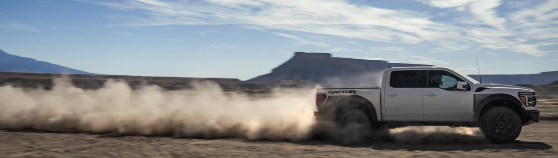 A v-formation of different colored 2023 Ford F-150s on a desert plain.