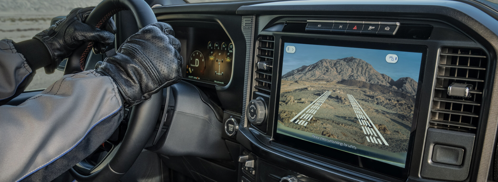 Five red, white, silver, blue, and black 2023 Ford F-150s sit parked facing the viewer on a dirt plain