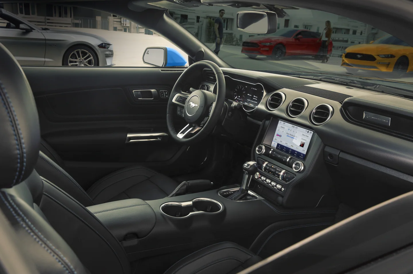 A view of the interior of a black leather upholstered and trimmed 2022 Ford Mustang with infotainment center mounted in the center of the dash, cupholders, and center console.