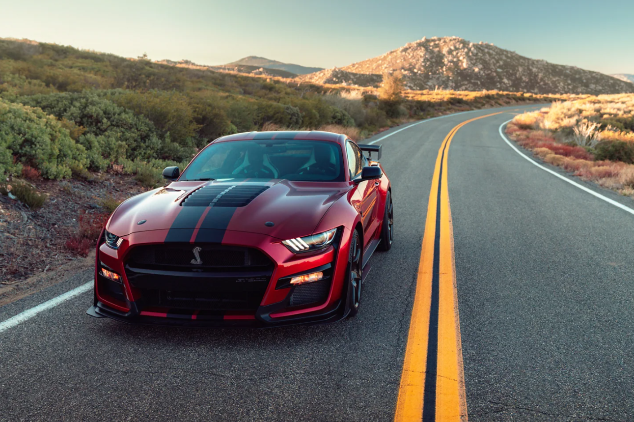 A red 2023 Ford Mustang driving in the road